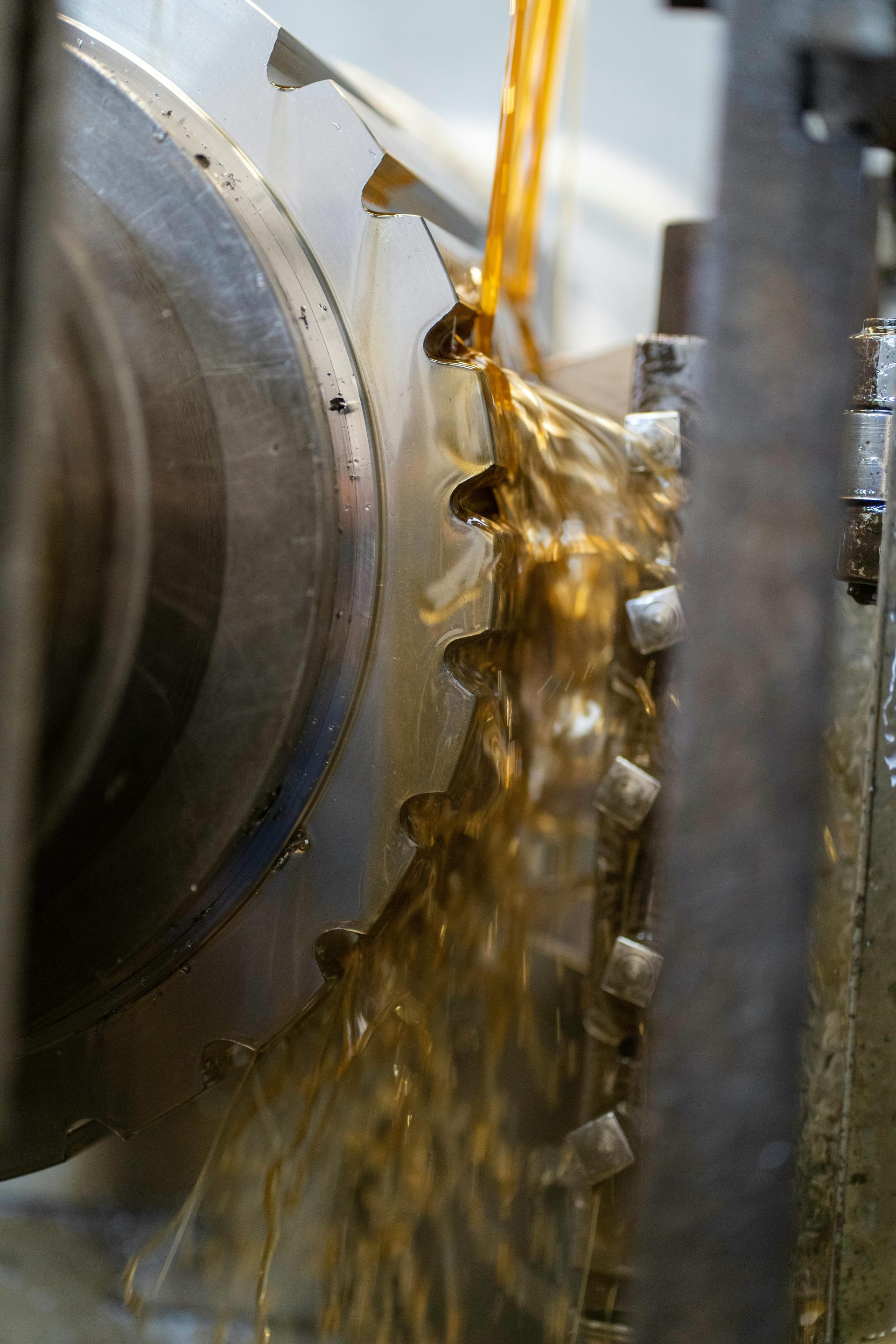 Primer plano de un engranaje que se está lubricando con aceite durante su fabricación.